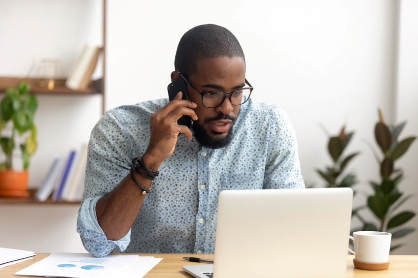 A man sitting at his desk, cold calling a customer.