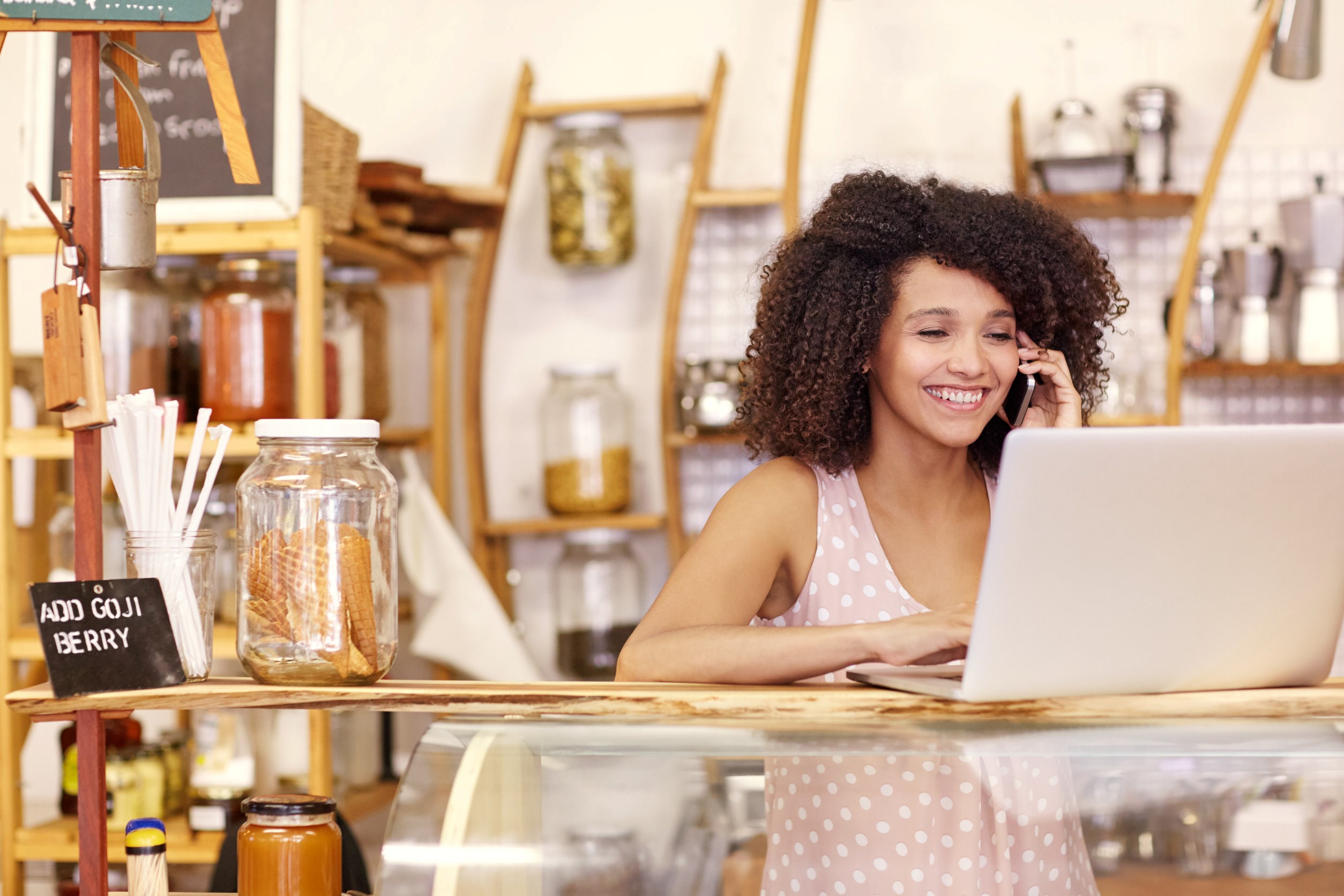 Image of a small business owner planning her marketing strategy on her laptop and phone.