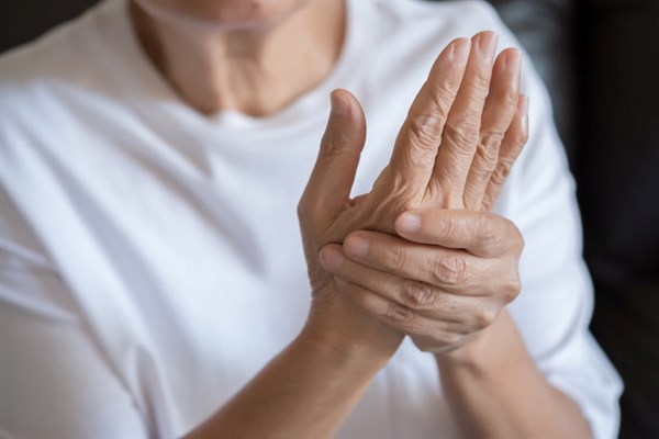 Image of a woman massaging her wrist and hand because of arthritis pain.